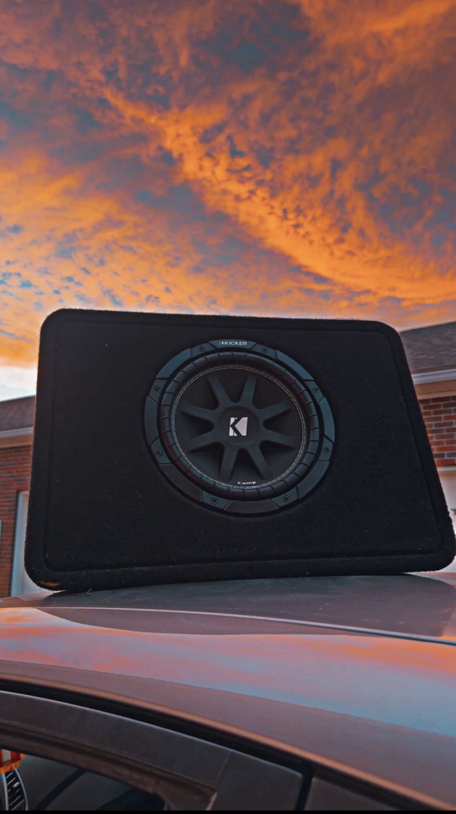 Kicker subwoofer enclosure mounted on a car at sunset